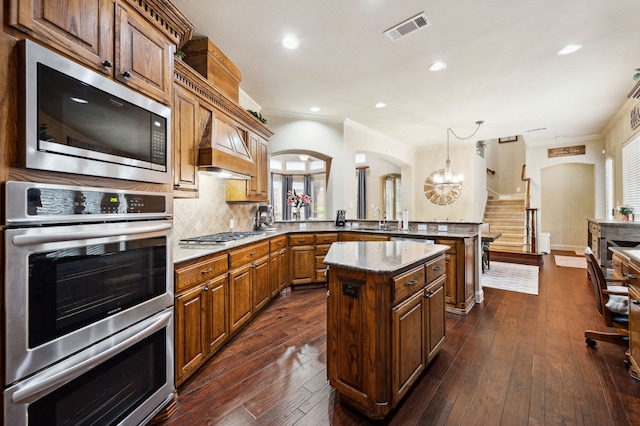 4651 Liam Dr, Frisco, TX 75034 - kitchen featuring stainless steel appliances, a peninsula, a sink, a kitchen island, and ornamental molding