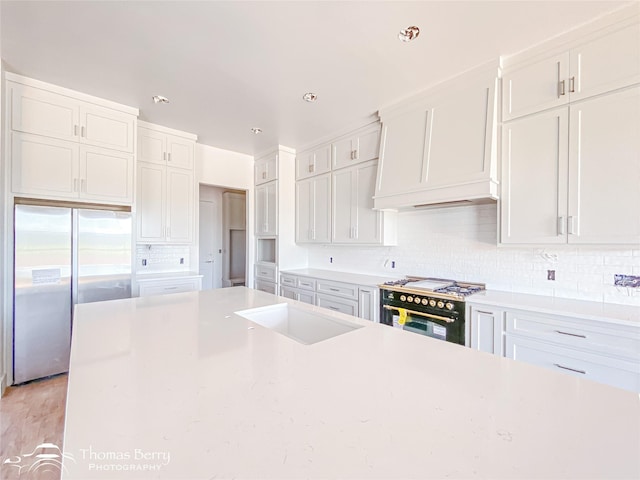 132 Pine Springs Cv, Tuscola, TX 79562 - kitchen featuring stainless steel fridge, range with two ovens, decorative backsplash, white cabinetry, and light countertops