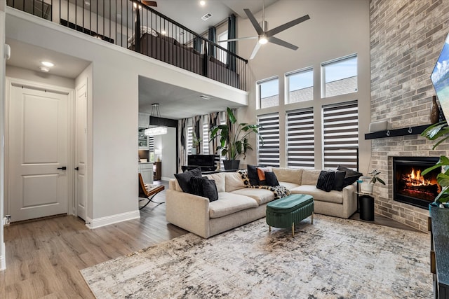 1806 Clouded Wren Dr, Arlington, TX 76005 - living area featuring ceiling fan, wood finished floors, a towering ceiling, a brick fireplace, and baseboards