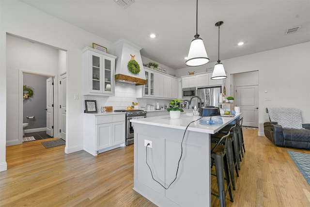 1511 Horseshoe Ct, Justin, TX 76247 - kitchen with stainless steel appliances, light countertops, a breakfast bar area, decorative backsplash, and white cabinetry