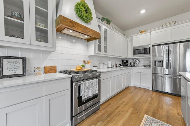 1511 Horseshoe Ct, Justin, TX 76247 - kitchen with appliances with stainless steel finishes, custom exhaust hood, light countertops, white cabinetry, and decorative backsplash