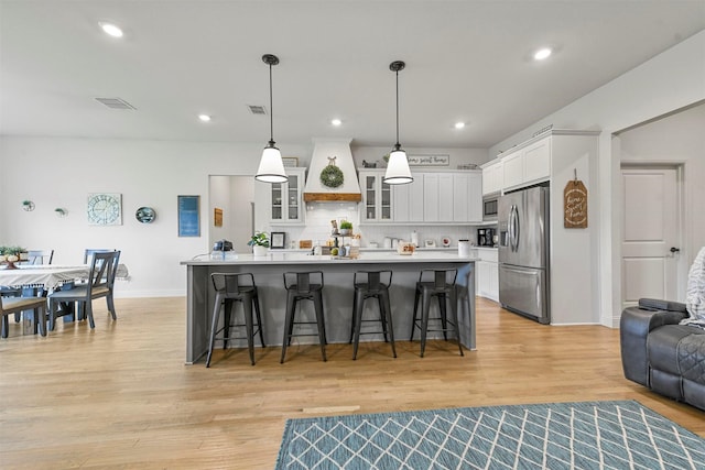 1511 Horseshoe Ct, Justin, TX 76247 - kitchen with stainless steel appliances, a breakfast bar area, light wood-type flooring, white cabinetry, and recessed lighting