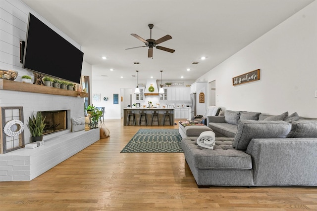 1511 Horseshoe Ct, Justin, TX 76247 - living room with ceiling fan, a brick fireplace, light wood-style floors, and recessed lighting