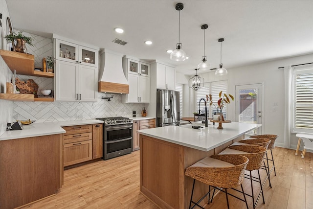 615 Louder Way, Fate, TX 75087 - kitchen with stainless steel appliances, custom range hood, open shelves, light wood-style floors, and backsplash