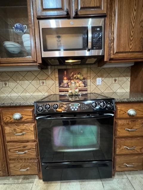 255 Chaparrals Run, Azle, TX 76020 - kitchen featuring stainless steel microwave, black range with electric stovetop, brown cabinets, and dark stone counters