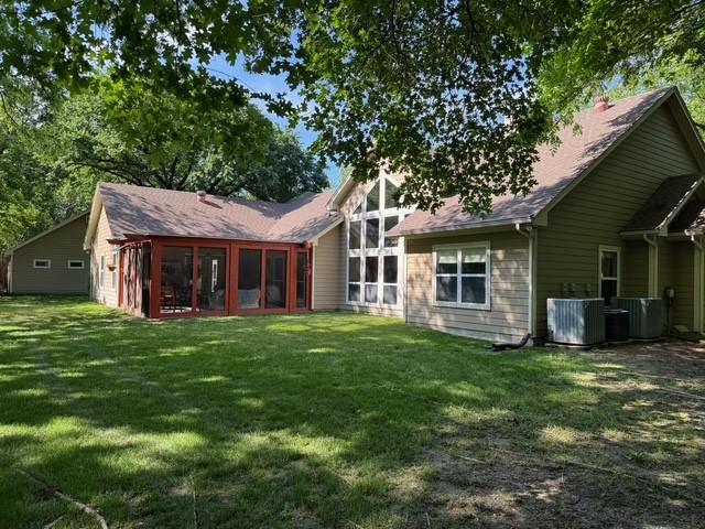 255 Chaparrals Run, Azle, TX 76020 - back of house with central air condition unit, a lawn, and a sunroom