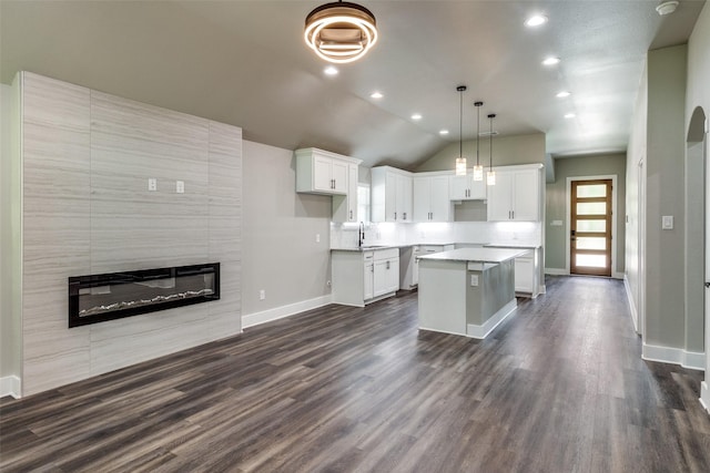 3235 Pine St, Dallas, TX 75215 - kitchen featuring baseboards, a kitchen island, a sink, white cabinets, and a tile fireplace