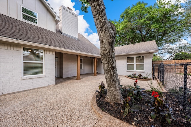 9916 Sandalwood Dr, Woodway, TX 76712 - view of exterior entry with brick siding, fence, a chimney, and a shingled roof