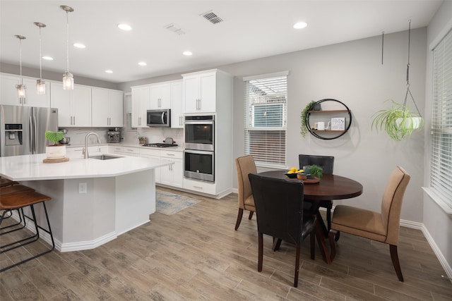 1619 Temperance Way, Wylie, TX 75098 - kitchen featuring stainless steel appliances, a sink, light wood-style floors, light countertops, and backsplash