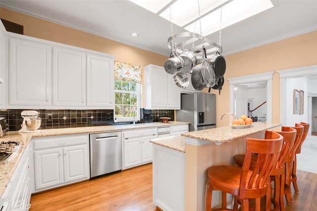 404 High Meadow Ln, Heath, TX 75032 - kitchen featuring appliances with stainless steel finishes, light wood-style floors, crown molding, a kitchen breakfast bar, and decorative backsplash