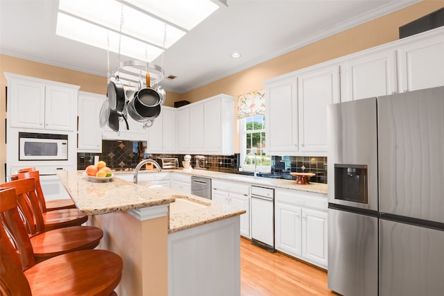 404 High Meadow Ln, Heath, TX 75032 - kitchen featuring stainless steel fridge, white microwave, a sink, white cabinetry, and ornamental molding