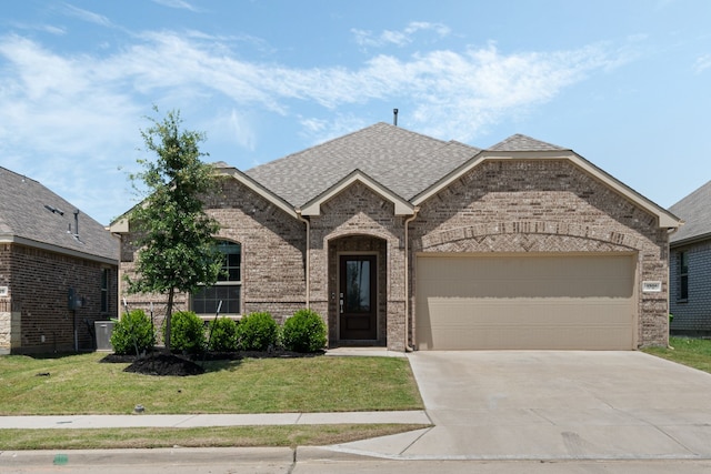 1701 Lake Grove Dr, Little Elm, TX 75068 - french country inspired facade with brick siding, concrete driveway, a garage, a front lawn, and a shingled roof