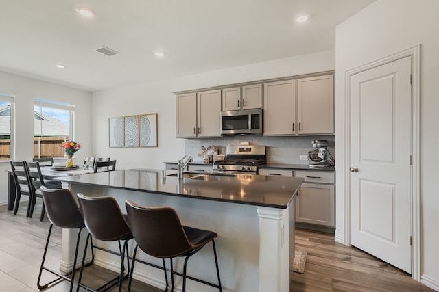 1701 Lake Grove Dr, Little Elm, TX 75068 - kitchen with appliances with stainless steel finishes, dark countertops, gray cabinetry, a sink, and a breakfast bar area