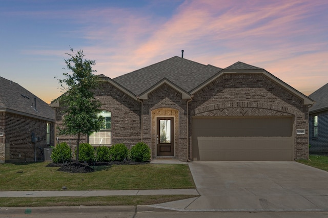 1701 Lake Grove Dr, Little Elm, TX 75068 - french provincial home featuring driveway, a garage, brick siding, a lawn, and a shingled roof