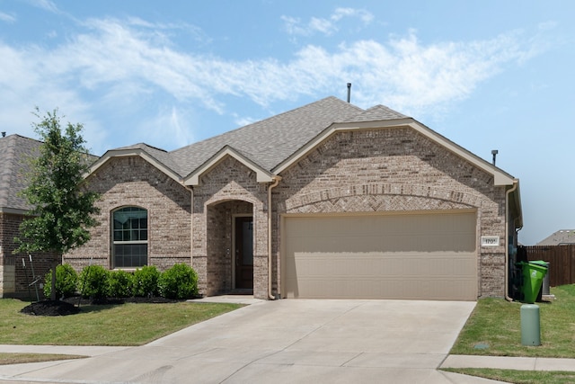 1701 Lake Grove Dr, Little Elm, TX 75068 - french country style house with concrete driveway, brick siding, an attached garage, and roof with shingles