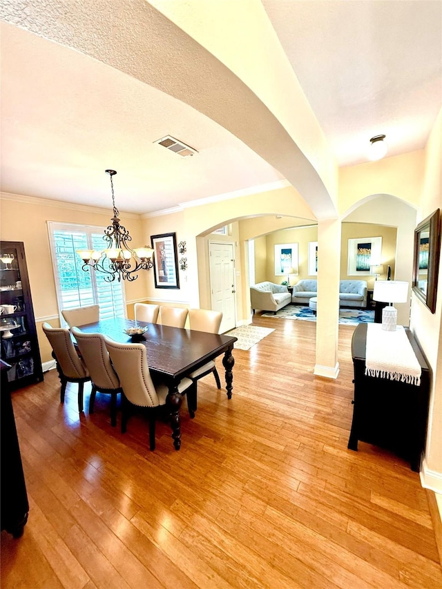 708 W Lonesome Dove Trl, Arlington, TX 76001 - dining room with arched walkways, light wood-style floors, ornamental molding, a chandelier, and baseboards