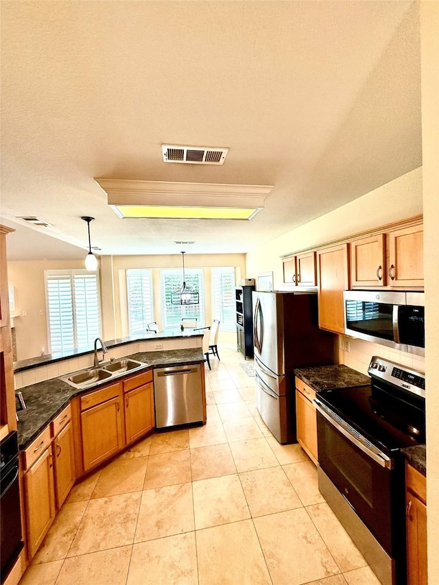 708 W Lonesome Dove Trl, Arlington, TX 76001 - kitchen featuring stainless steel appliances, a sink, pendant lighting, brown cabinets, and a peninsula
