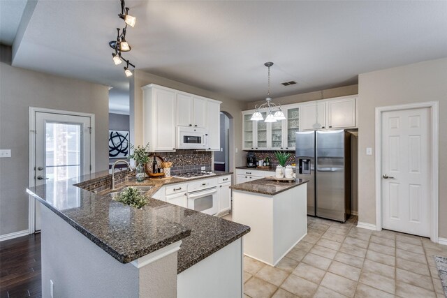 851 Sibyl Ln, Prosper, TX 75078 - kitchen with white appliances, a sink, a peninsula, decorative backsplash, and a center island