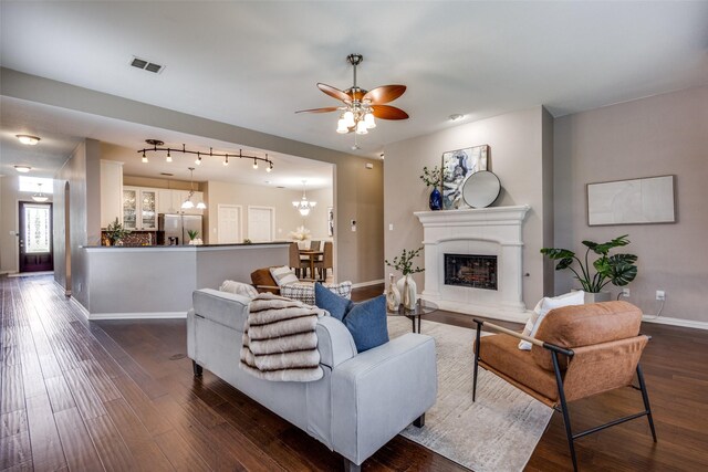 851 Sibyl Ln, Prosper, TX 75078 - living room with a chandelier, a fireplace with raised hearth, dark wood-type flooring, ceiling fan, and baseboards