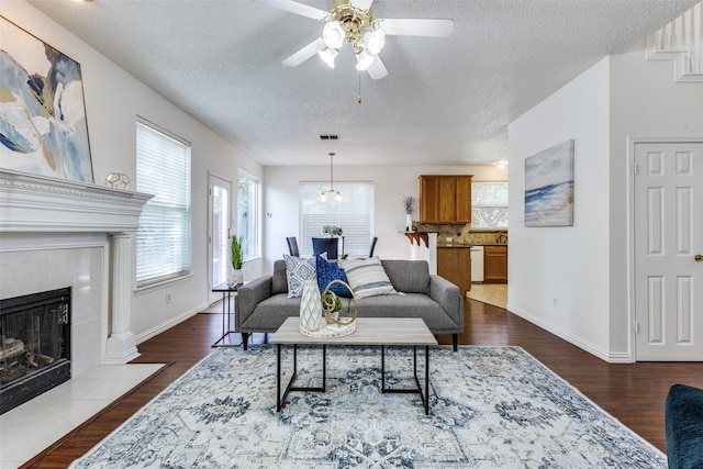 3717 Drew Dr, Frisco, TX 75035 - living area featuring a tiled fireplace, a ceiling fan, a textured ceiling, dark wood-type flooring, and baseboards
