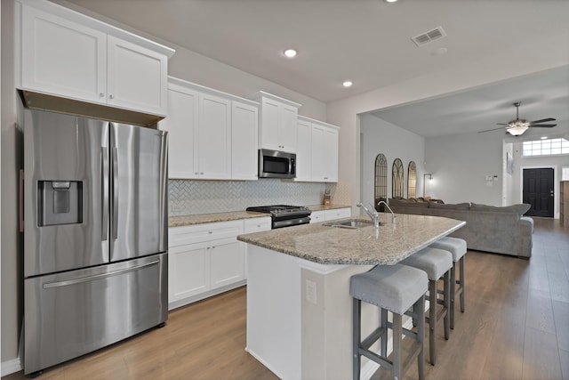 3935 Chesapeake Ln, Crandall, TX 75114 - kitchen featuring stainless steel appliances, white cabinets, decorative backsplash, wood finished floors, and ceiling fan