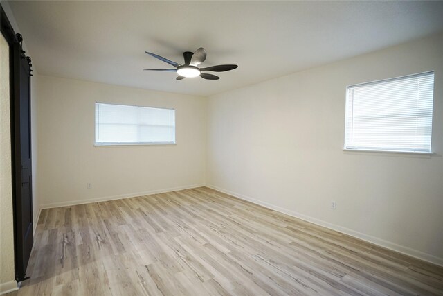 2409 Sunset Ln, Burleson, TX 76028 - spare room with light wood finished floors, a ceiling fan, baseboards, and a barn door
