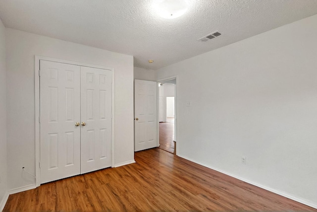 232 Cotton Wood Ct, Rockwall, TX 75032 - unfurnished bedroom featuring wood finished floors, a closet, baseboards, and a textured ceiling