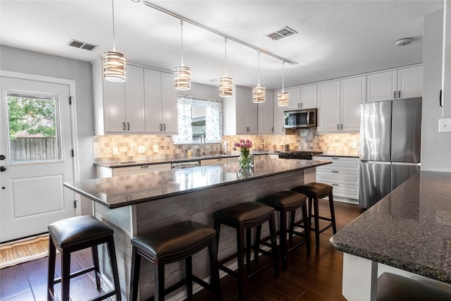 kitchen featuring stainless steel appliances, dark wood-style flooring, plenty of natural light, and white cabinets