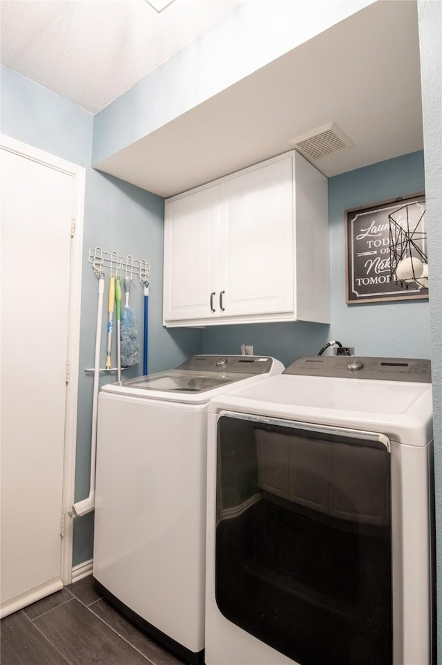 clothes washing area featuring cabinet space, washer and clothes dryer, dark wood-style flooring, and baseboards