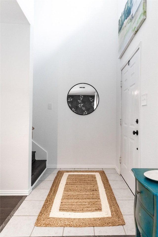 entrance foyer featuring stairs, light tile patterned floors, and baseboards