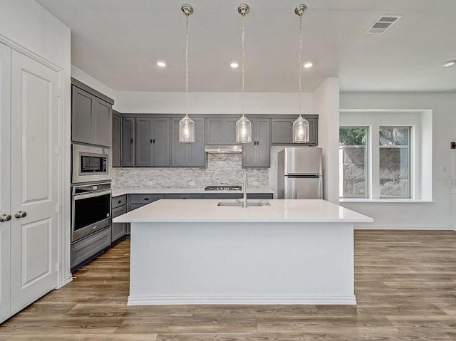 240 Harper St, Irving, TX 75063 - kitchen with appliances with stainless steel finishes, gray cabinets, under cabinet range hood, a sink, and tasteful backsplash