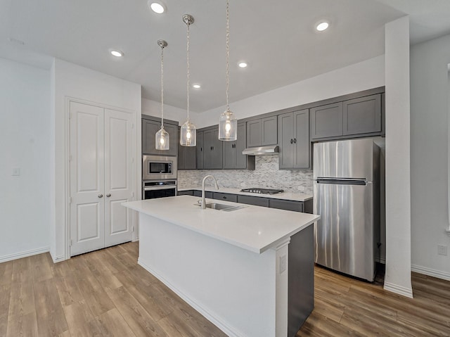 240 Harper St, Irving, TX 75063 - kitchen with stainless steel appliances, a sink, light countertops, wood finished floors, and a center island with sink