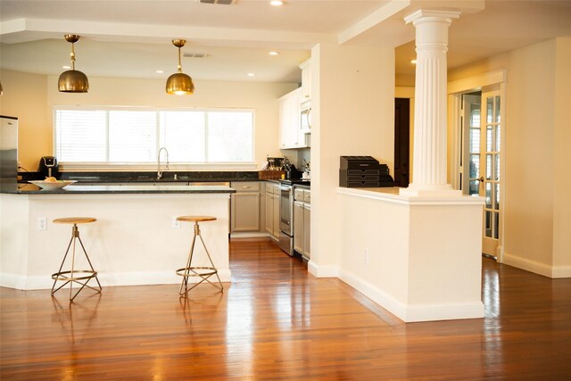 6318 White Oaks Ln, Frisco, TX 75035 - kitchen with stainless steel electric stove, ornate columns, dark countertops, a peninsula, and wood finished floors