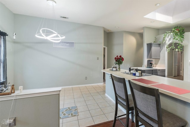 809 Fox Run Trl, Saginaw, TX 76179 - kitchen featuring a sink, gray cabinetry, light countertops, light tile patterned flooring, and a skylight