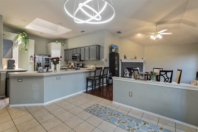 809 Fox Run Trl, Saginaw, TX 76179 - kitchen with stainless steel appliances, a peninsula, light tile patterned floors, light countertops, and gray cabinetry