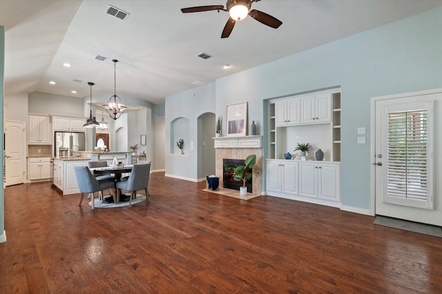 413 Sloan Creek Pkwy, Fairview, TX 75069 - living room featuring a ceiling fan, a tile fireplace, dark wood-style floors, lofted ceiling, and arched walkways