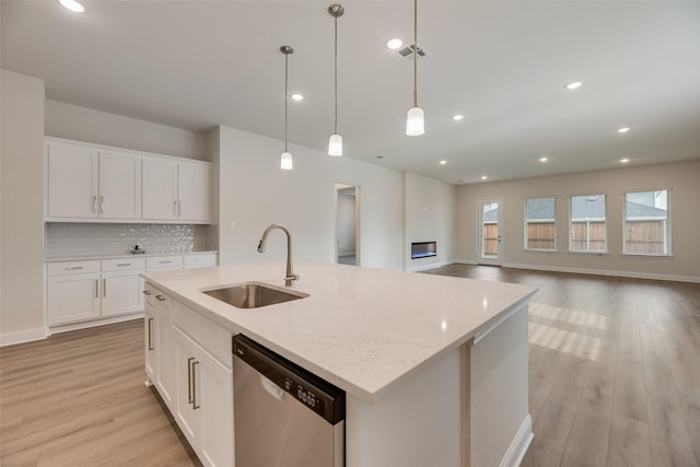 7104 Manhattan Dr, Rowlett, TX 75088 - kitchen featuring stainless steel dishwasher, a sink, light wood-type flooring, an island with sink, and decorative light fixtures
