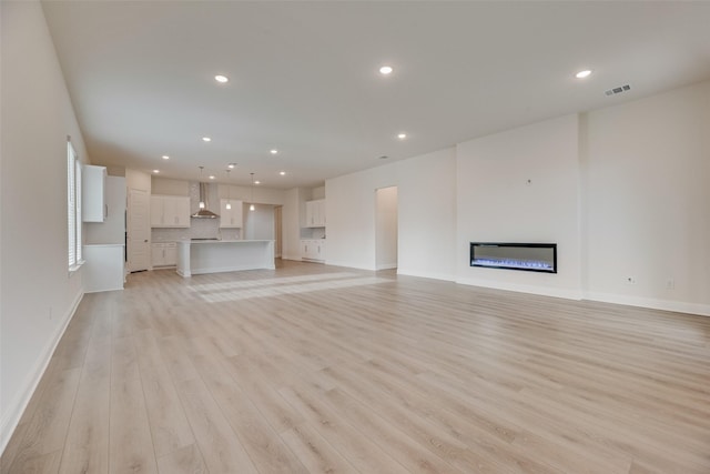 7104 Manhattan Dr, Rowlett, TX 75088 - unfurnished living room with light wood-style flooring, a glass covered fireplace, recessed lighting, and baseboards