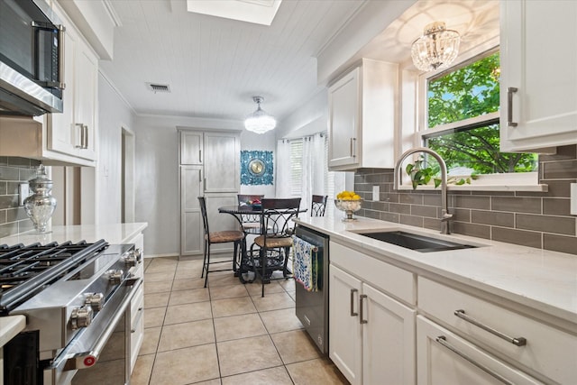 4021 Tracey Trl, Rowlett, TX 75088 - kitchen with appliances with stainless steel finishes, a sink, tasteful backsplash, light tile patterned floors, and a skylight