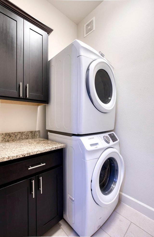 5005 Meridian Ln Unit 3102, Addison, TX 75001 - laundry room with stacked washer / dryer, cabinet space, light tile patterned floors, and baseboards