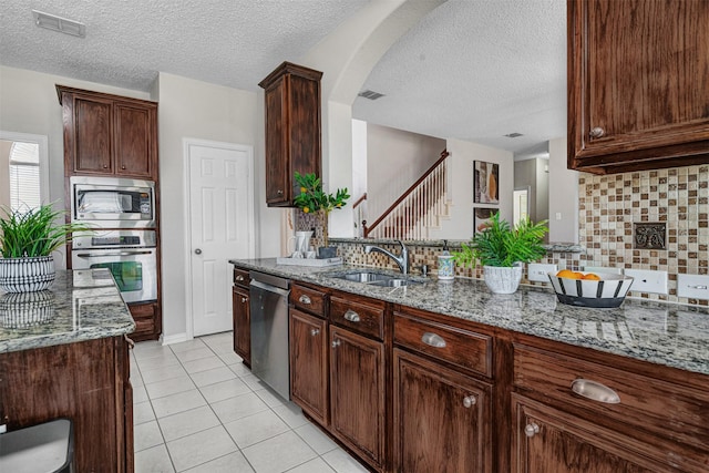3501 Thorp Springs Dr, Plano, TX 75025 - kitchen with stainless steel appliances, a textured ceiling, a sink, light stone counters, and backsplash