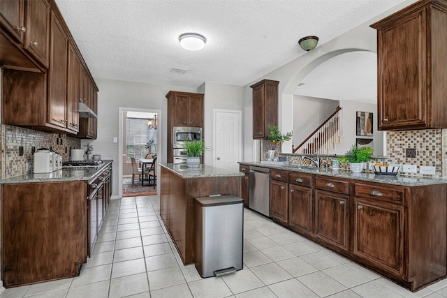 3501 Thorp Springs Dr, Plano, TX 75025 - kitchen featuring stainless steel appliances, tasteful backsplash, stone countertops, a textured ceiling, and a kitchen island