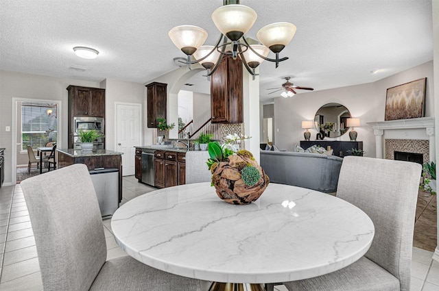 3501 Thorp Springs Dr, Plano, TX 75025 - dining space featuring a ceiling fan, a tiled fireplace, a textured ceiling, stairway, and arched walkways