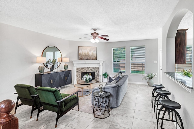3501 Thorp Springs Dr, Plano, TX 75025 - living area with a ceiling fan, arched walkways, plenty of natural light, a tile fireplace, and a textured ceiling