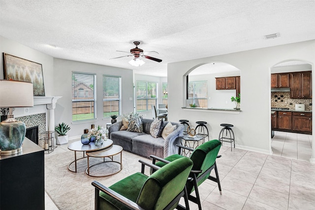 3501 Thorp Springs Dr, Plano, TX 75025 - living room featuring ceiling fan, light tile patterned flooring, baseboards, a fireplace, and a textured ceiling