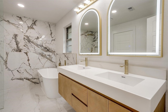 2317 Vega St, Grand Prairie, TX 75050 - bathroom featuring a freestanding bath, recessed lighting, double vanity, marble tiled floors, and tile walls