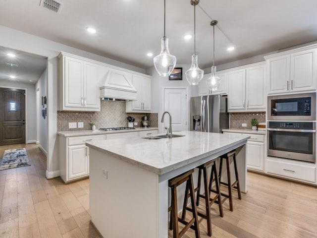 217 Fulton St, Oak Point, TX 75068 - kitchen with appliances with stainless steel finishes, a sink, custom exhaust hood, a breakfast bar area, and white cabinetry