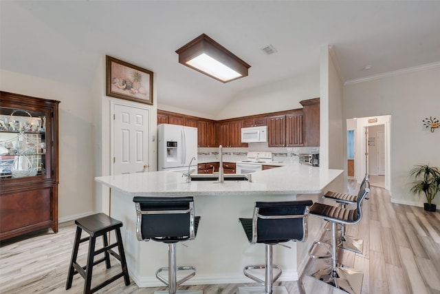 6729 Lucas Ln, North Richland Hills, TX 76182 - kitchen with white appliances, a sink, a breakfast bar, a peninsula, and light wood-style flooring