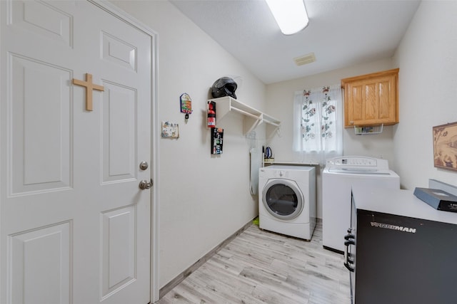 6729 Lucas Ln, North Richland Hills, TX 76182 - clothes washing area featuring washer and clothes dryer, cabinet space, light wood finished floors, and baseboards