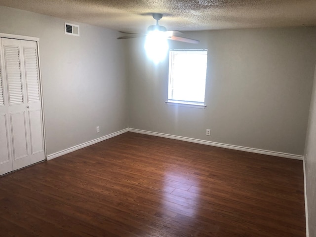 2149 Fleur De Lis Ct Unit 4, Arlington, TX 76012 - unfurnished bedroom featuring dark wood-type flooring, baseboards, a textured ceiling, a ceiling fan, and a closet